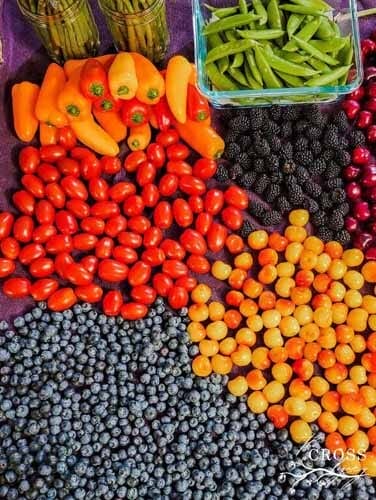 A colorful spread of fresh produce: Blueberries, Grape Tomatoes, Blackberries, Peppers, Cherries, Snap Peas, and Asparagus.