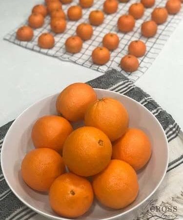 How Long Does an Orange Last? Oranges and Clementines on the counter in a white bowl and on an tea towel.