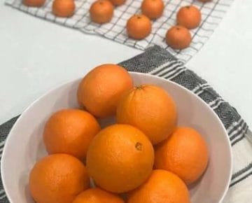 橙子能吃多久?柜台上的橘子和小柑橘放在一个白色的碗里，放在一块茶巾上。
