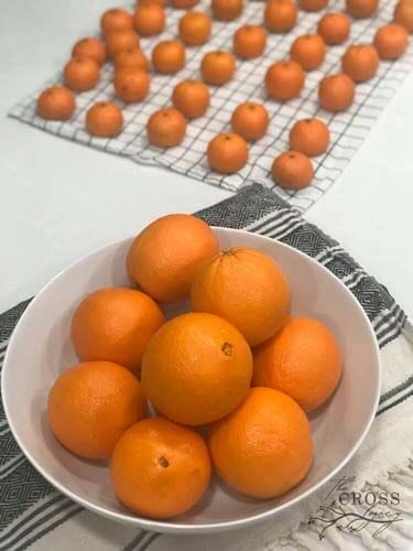 橙子能吃多久?柜台上的橘子和小柑橘放在一个白色的碗里，放在一块茶巾上。