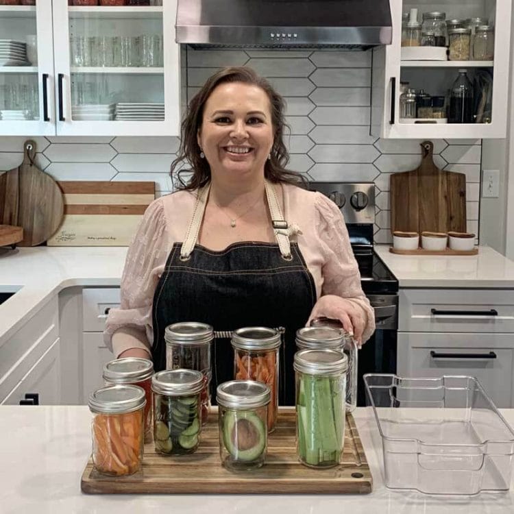 Amy Cross in her kitchen with freshly washed produce in glass mason jars.