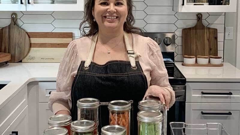 Amy Cross in her kitchen with freshly washed salad toppings in glass mason jars.