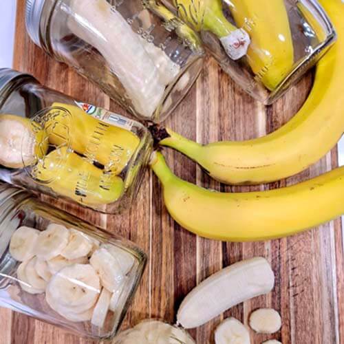 whole-bananas-cut-bananas-and-bananas-in-mason-jars-laid-out-on-a-wooden-cutting-board