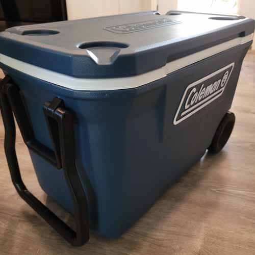 Large blue Coleman cooler with wheels and a handle.