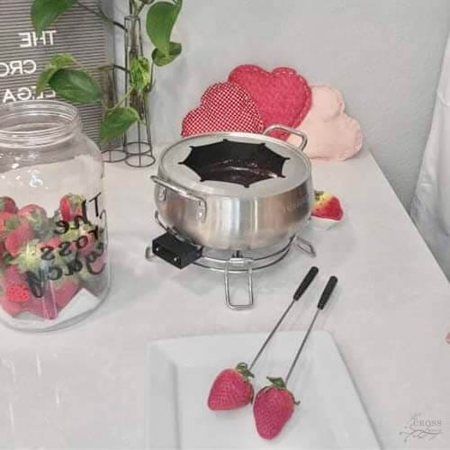 fondue pot all ready to go with strawberries next to strawberries in a jar and Valentines Day themed items on counter