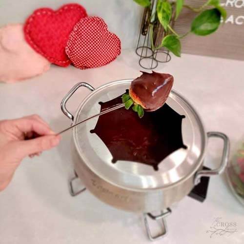strawberry dipped in chocolate fondue on a skewer