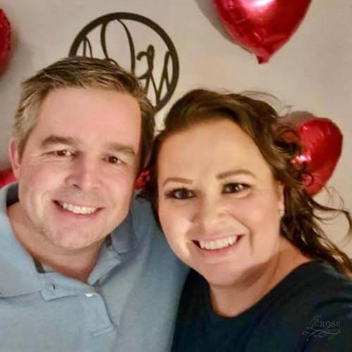 Mike and Amy in front of a wall of heart-shaped balloons
