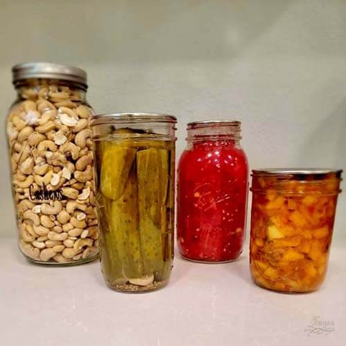 glass jars with canned tomatoes, pickles, and cashews