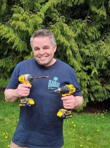 Mike holding a couple of power tools in the yard