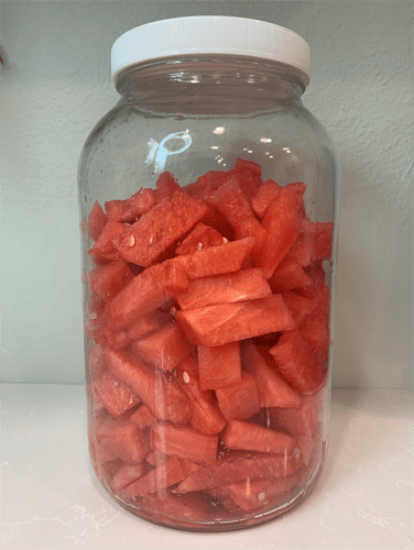 cut-watermelon-pieces-in-a-glass-gallon-jar-on-the-kitchen-counter