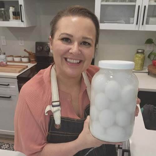 amy-cross-holding-a-jar-of-water-glass-eggs-in-her-kitchen