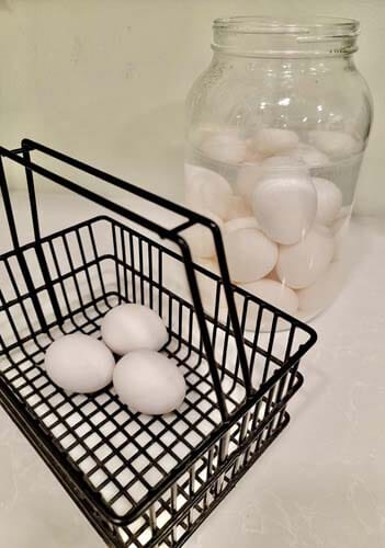farm-fresh-eggs-in-a-basket-and-water-glassed-eggs-in-a-jar-on-a-counter