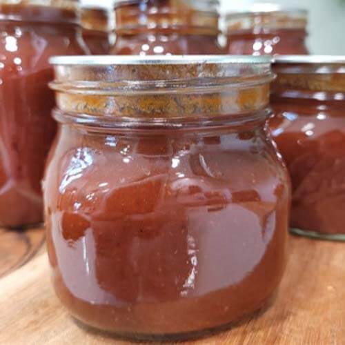 close-up-of-bbq-sauce-in-glass-mason-jars-sitting-on-a-wooden-cutting-boardgydF4y2Ba