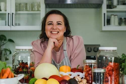 amy-cross-at-her-kitchen-counter-with-a-spread-of-fresh-produce-for-her-happy-1st-anniversary-photo-shoot-of-her-business