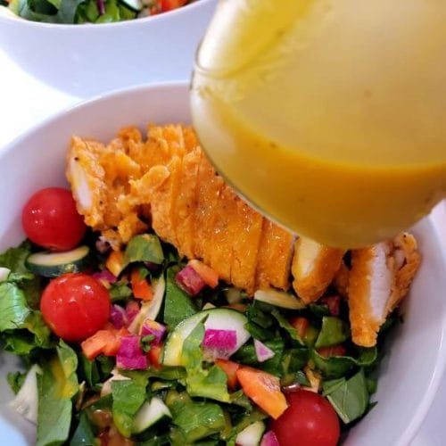 close-up-of-honey-mustard-salad-dressing-with-a-mixed-green-salad-with-chopped-chicken-strips
