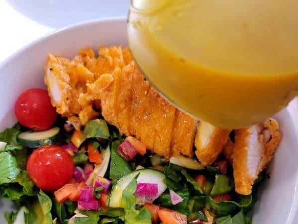 close-up-of-honey-mustard-salad-dressing-with-a-mixed-green-salad-with-chopped-chicken-strips