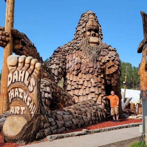 mike-cross-posing-with-Dahl 's-chainsaw-art-of-the-biggest-bigfoot