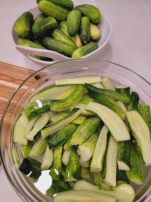sliced pickles soaking in a bowl of water