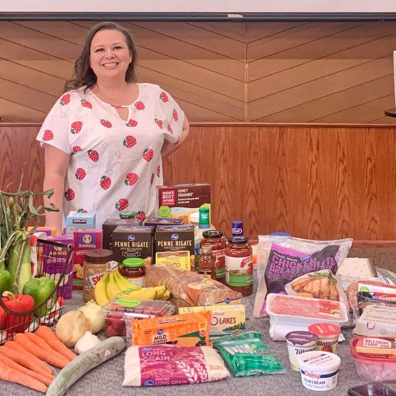 Amy behind a table with $135 worth of groceries