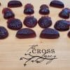 strawberry shaped elderberry gummies sitting on a wooden cutting board with The Cross Legacy logo engraved on it
