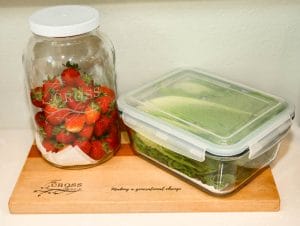 新鲜草莓和长叶莴苣装在玻璃罐里，放在木砧板上。