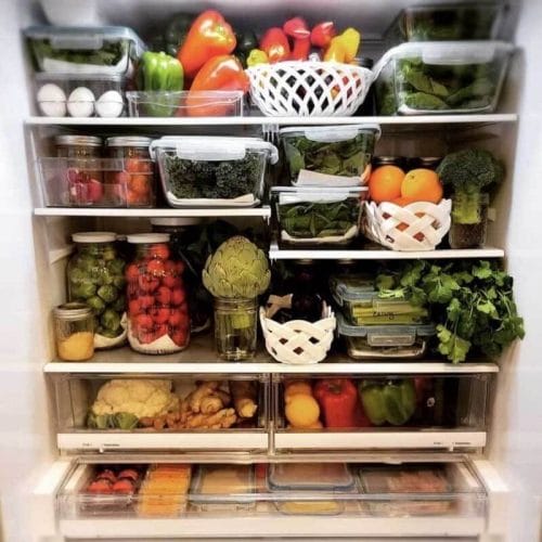 洋蓟能在冰箱里放多久?艾米·克洛斯都能坚持三周!冰箱里装满新鲜农产品，清洗后储存在玻璃储存容器中。