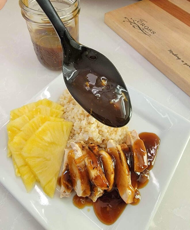 White plate with fresh sliced pineapple, brown rice, and chicken with homemade teriyaki sauce.