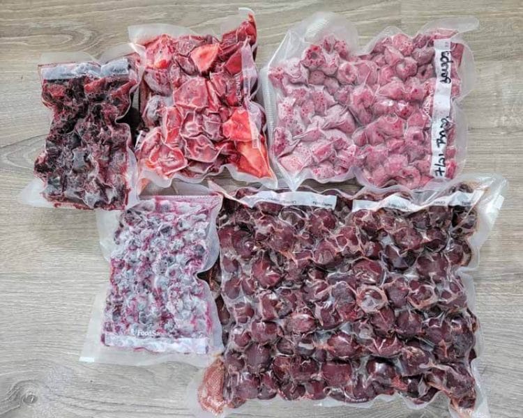 Frozen Berries in Vacuum Sealed Bags laying on a wooden table.
