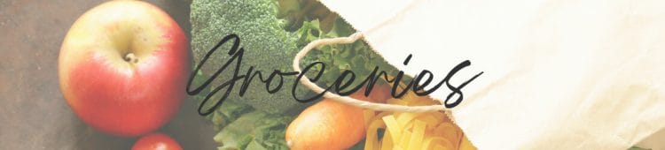 Brown paper grocery bag laying on its side with fresh produce spilling out onto a wooden table. Category page header image - grocery page.