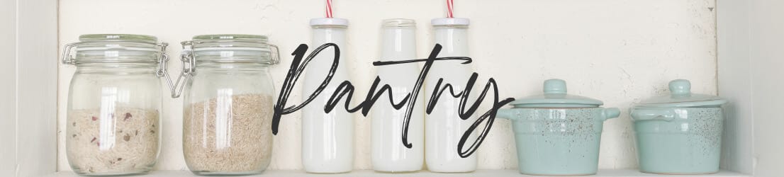 White pantry shelves with glass jars containing grains and pasta. Three white ceramic bottles, and 3 aqua crocks with lids. Category Page Header Image for Pantry page.