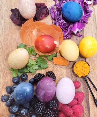 Naturally dyed Easter Egg on a cutting board with their corresponding dyed ingredients.
