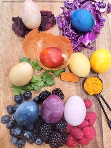 Naturally dyed Easter Egg on a cutting board with their corresponding dyed ingredients.