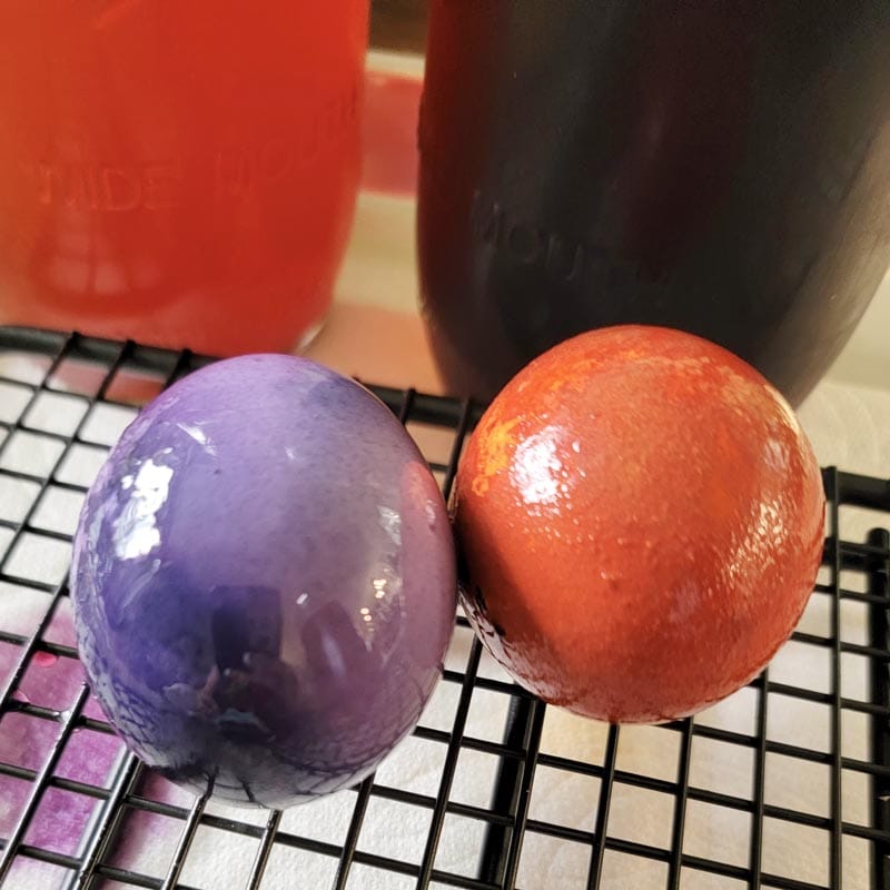 Two hard-boiled egg drying on a cooling rack.