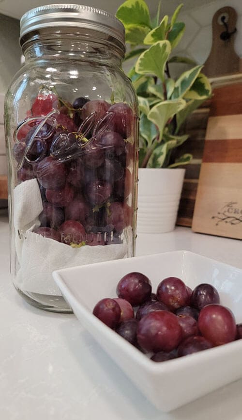 Grapes in a white square dish and store grapes in an airtight glass jar with a lid.