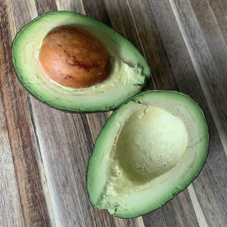 A beautiful avocado on a wooden cutting board - showing you how to pick the perfect avocado.