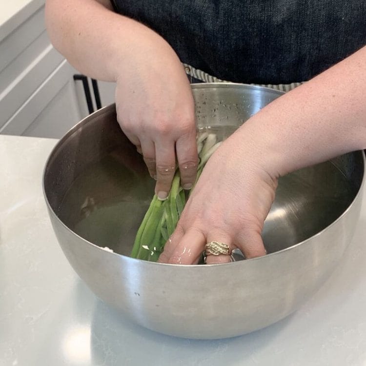 Soaking green onions in a vinegar bath for two minutes.