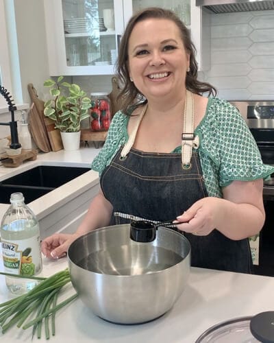 Amy in her kitchen washing fresh green onions in a vinegar bath.