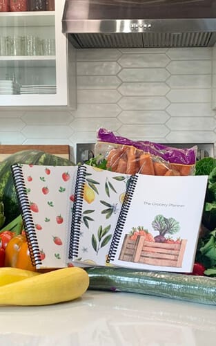 Grocery Guide and Meal Planners on Amy's Kitchen Counter with a fresh produce spread.