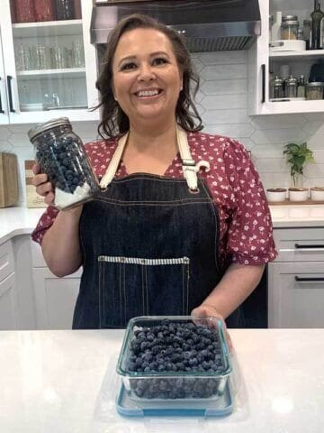 Amy Cross holding a mason jar of blueberries in her kitchen