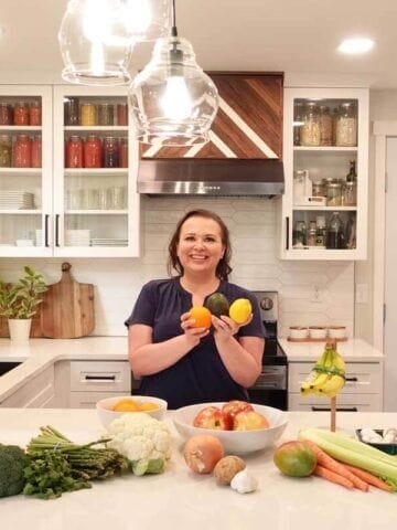 Amy Cross in her kitchen with a spread of produce teaching how to store fruits and vegetables.
