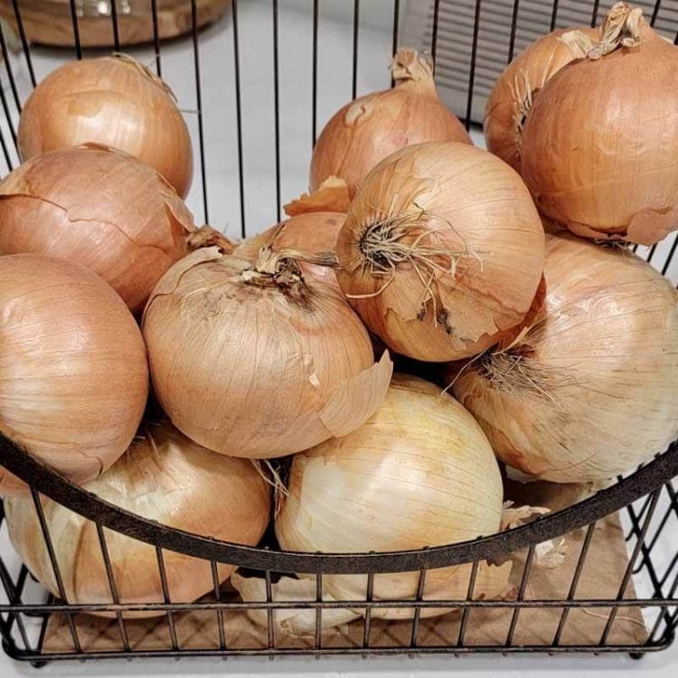 Onions in a wire basket on the counter.