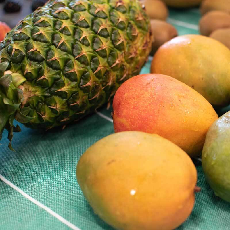 Mangos and a Pineapple drying on a towel on the counter.