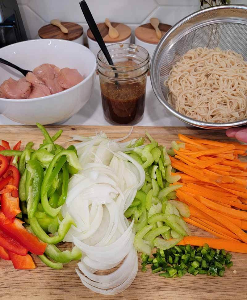 Bowl of chicken, cooked gluten free noodles, red and green peppers, onions, celery, carrots, and homemade Yakisoba sauce.