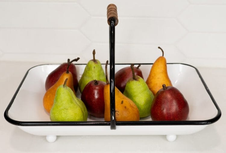 Variety of fresh pears on a white tray with black handle.