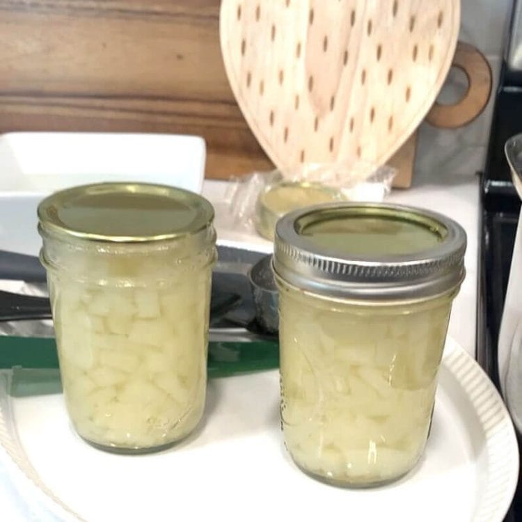 2 jars of preserved pears on a white plate. One with the ring on, and one with the metal ring removed.