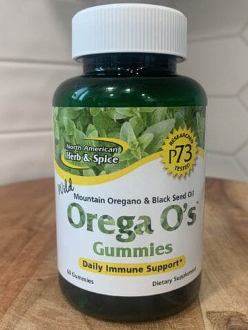 Bottle of Orega O's Gummies sitting on a wooden cutting board, which contains real oregano oil.