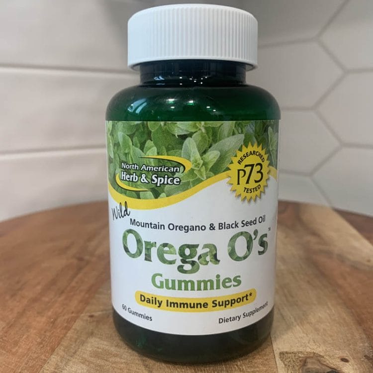 Bottle of Orega O's Gummies sitting on a wooden cutting board, which contains real oregano oil.