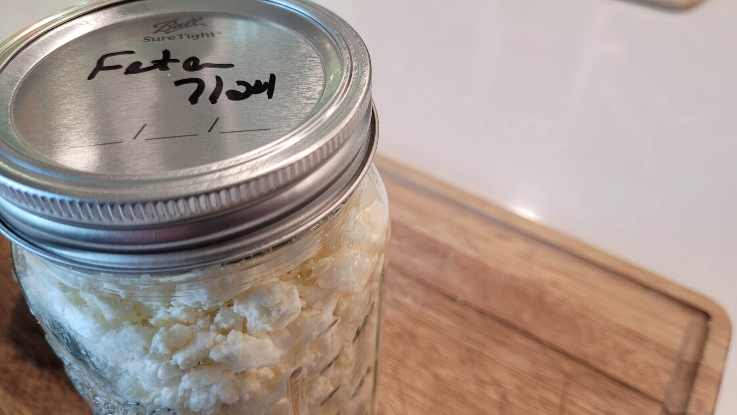 Glass jar with feta cheese inside of it with a metal lid 