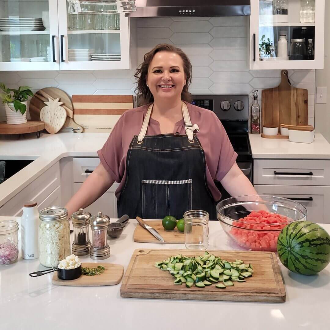 Amy Cross with all of the ingredients for Watermelon Feta Salad on the kitchen counter.