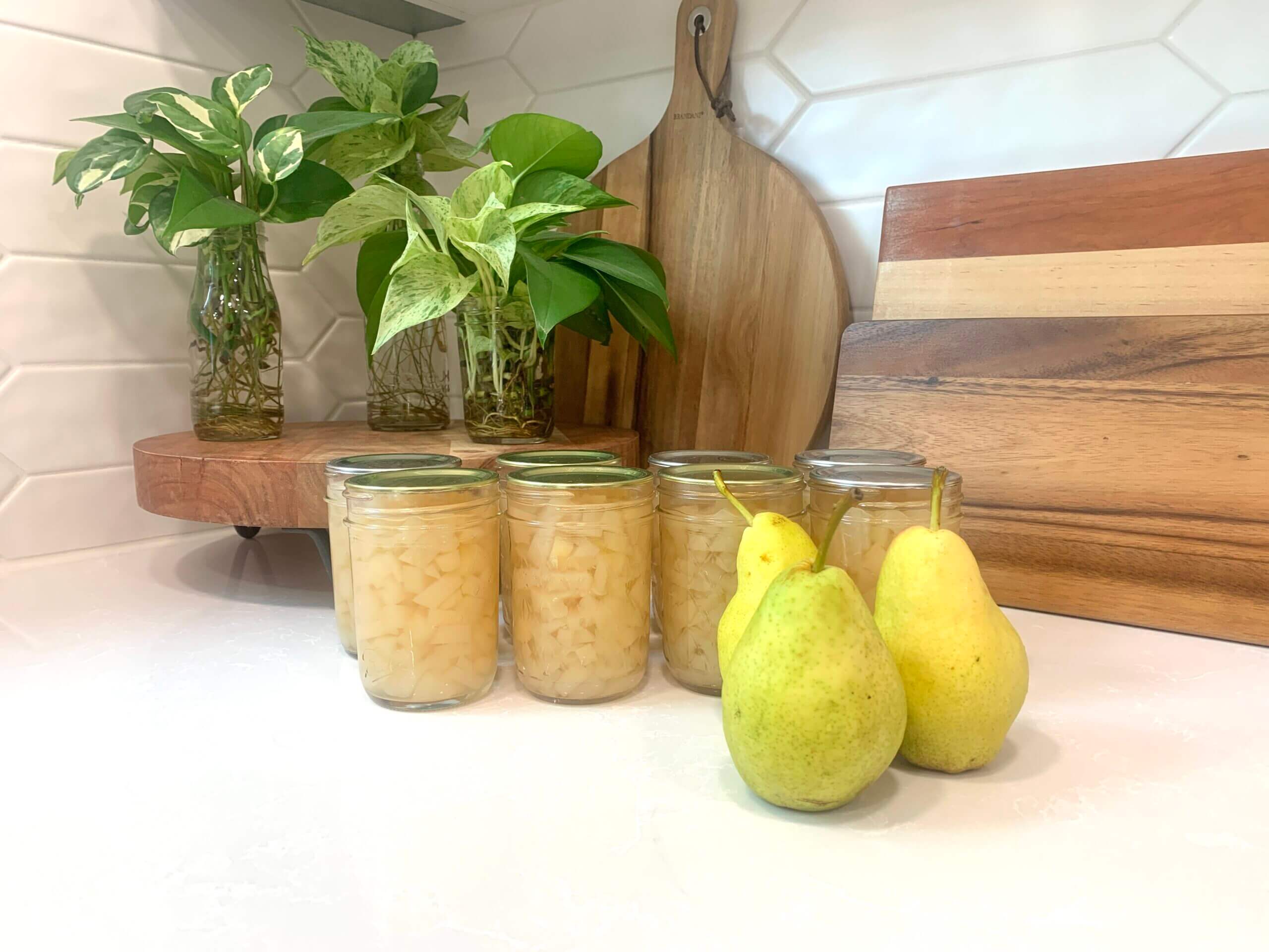 freshly canned pears on the counter with fresh pears 